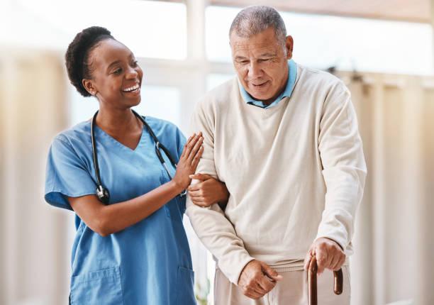 A nurse smiling with an older patient using a cane